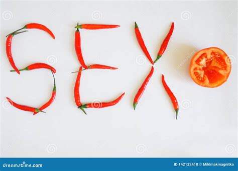 Red Chili Peppers And Half A Tomato On A White Surface Laid Out The