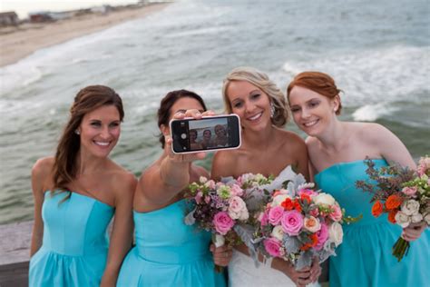 Three Bridesmaids Taking A Photo With Their Cell Phone On The Pier By The Ocean