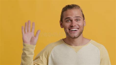 Hello Friendly Young Guy Waving Hand At Camera Standing On Yellow