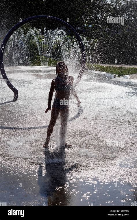 A Young Girl Playing In Water Fountains On A Hot Summers Day Stock