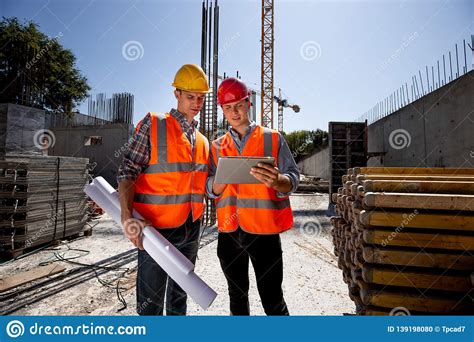 Civil Architect And Construction Manager Dressed In Orange Work Vests