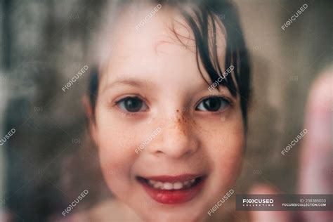 Portrait Of A Smiling Girl Looking Through The Wet Shower Glass