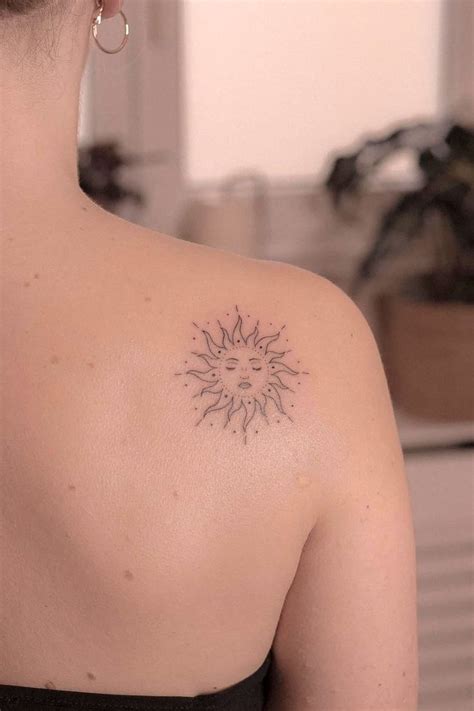 The Back Of A Woman S Shoulder With A Small Sun Tattoo On Her Left Shoulder
