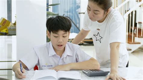 slow motion of asian mother helping her son doing homework on white table serious asian mother