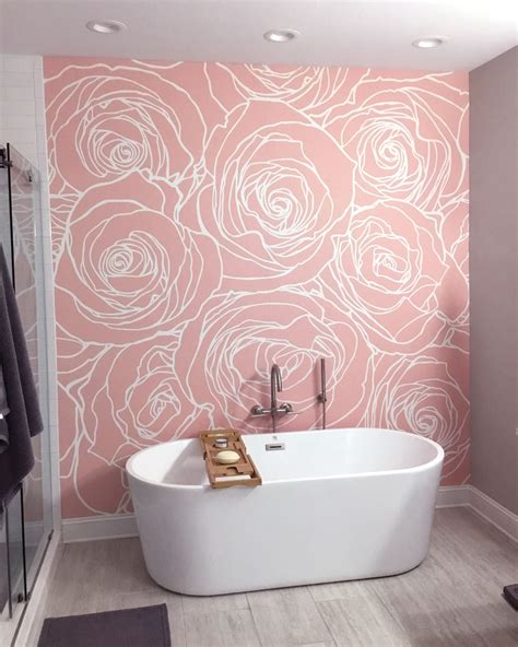 A White Bath Tub Sitting Next To A Wall With Flowers On The Side Of It