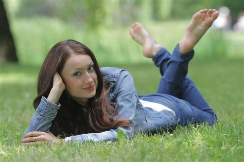 A Woman Laying In The Grass With Her Feet Up And Arms Behind Her Head
