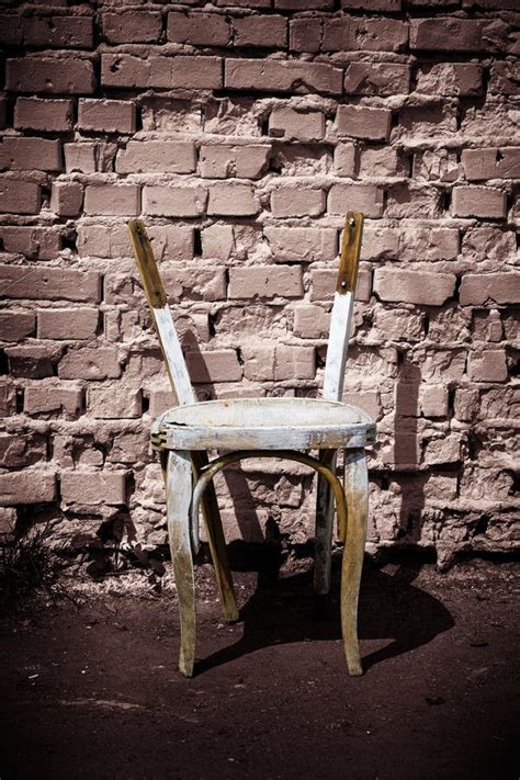 Old Wooden Chair Without Backrest Against A Brick Wall Background Stock