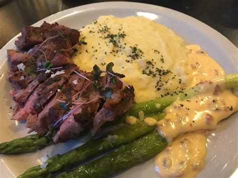 A White Plate Topped With Meat Mashed Potatoes And Asparagus