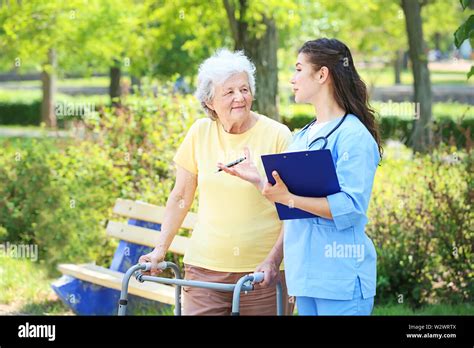Caregiver Walking With Senior Woman In Park Stock Photo Alamy