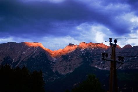 Glowing Mountain Peaks In The Sunset With Rain Clouds Stock Photo