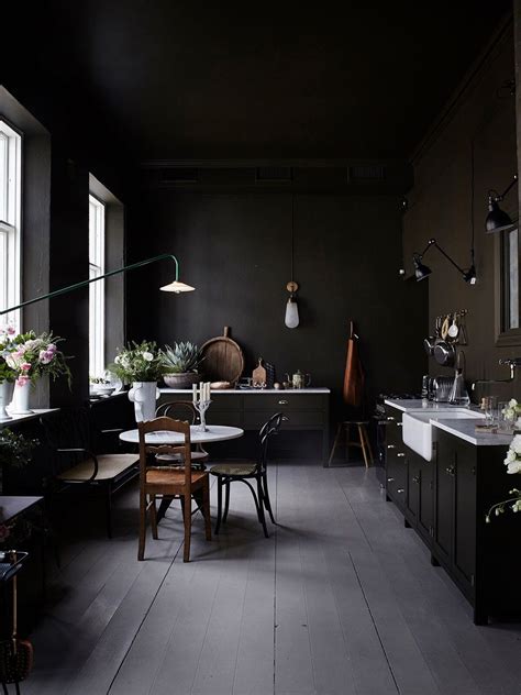 A Kitchen With Black Walls And Wooden Flooring Next To A Dining Room