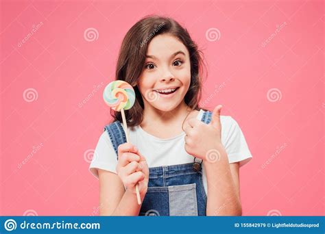 Smiling Child Holding Lollipop And Showing Thumb Up Isolated Stock