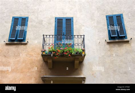 A Small Balcony On A House And Blue Painted Shutters At The