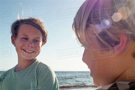 Head And Shoulders Portrait Of Two Smiling Boys Standing By The Ocean