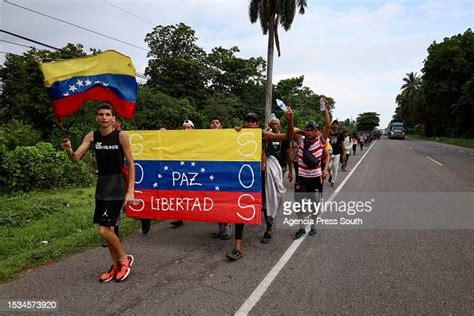 Migrants Holding Flags Of Venezuela Walk As Part Of A Migrant Caravan