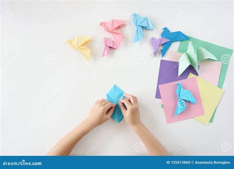 Children`s Hands Do Origami From Colored Paper On White Background