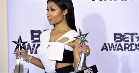A Woman Holding Two Awards In Her Hands And Wearing A White Top With