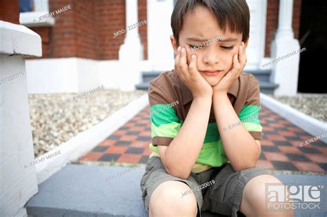 Sad Little Boy Sitting On Front Steps Of House Close Up Stock Photo
