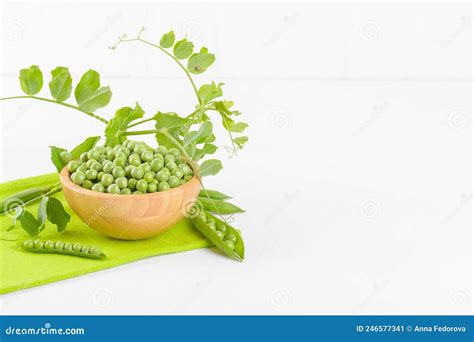 Fresh Green Peas In A Wooden Bowl With Peas Plants Leaves On A Green