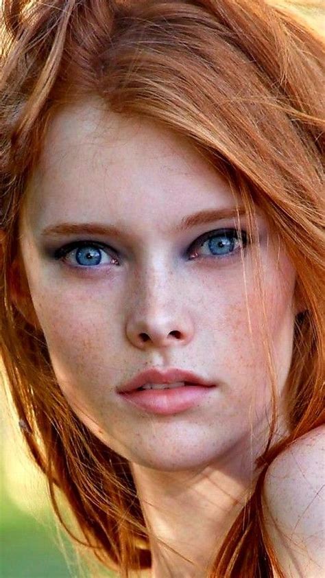 A Woman With Red Hair And Blue Eyes Is Looking At The Camera While Shes Holding