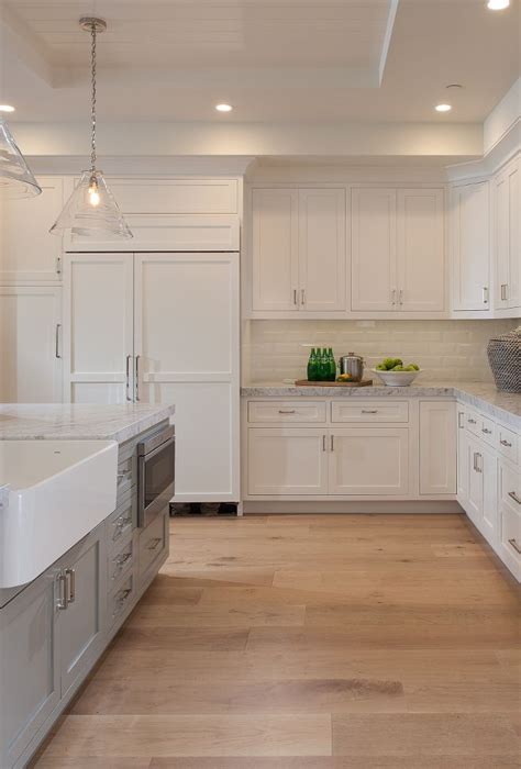 Off white kitchen cabinets with grey walls. Flooring is 3/4″ x 7″ wood floor planks stained in a Light ...
