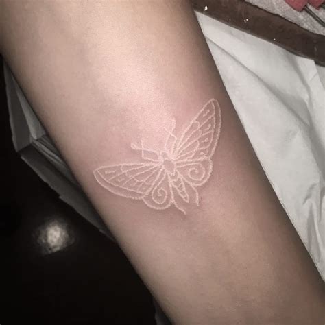 A Small White Butterfly Tattoo On The Arm