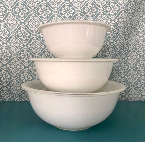 Three White Bowls Stacked On Top Of Each Other In Front Of A Blue And