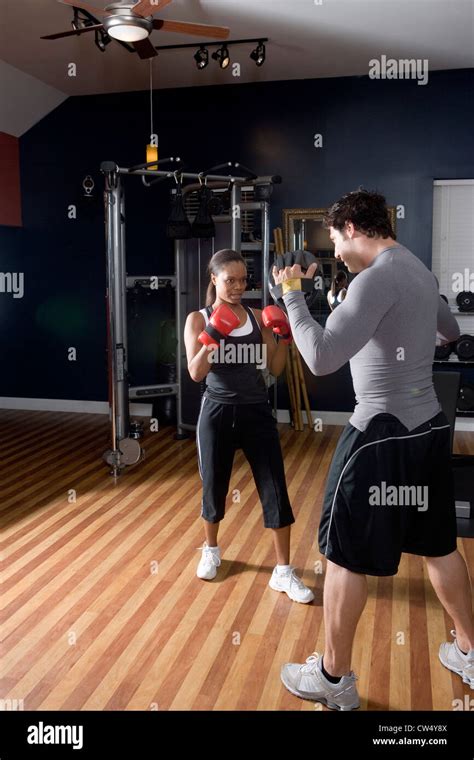 Trainer Instructing A Young Woman With Boxing Equipment In The Gym