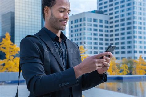 Black Businessman Using Mobile Phone App Texting Outside Of Office In