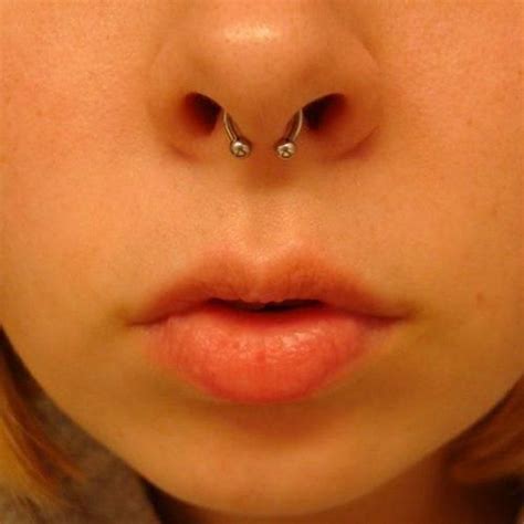 A Close Up Of A Person With Piercings On Their Nose And Nose Ring In