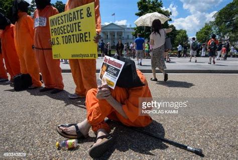 Protestors Wearing Orange Prisoners Jumpsuits Hold Signs As They