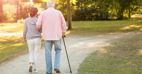 Senior Woman And Caregiver Go Walking Outdoors