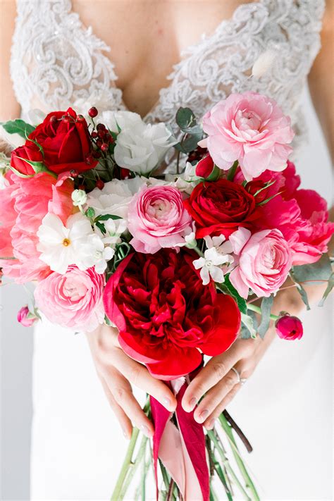 A Bride Holding A Bouquet Of Red And Pink Flowers On Her Wedding Day