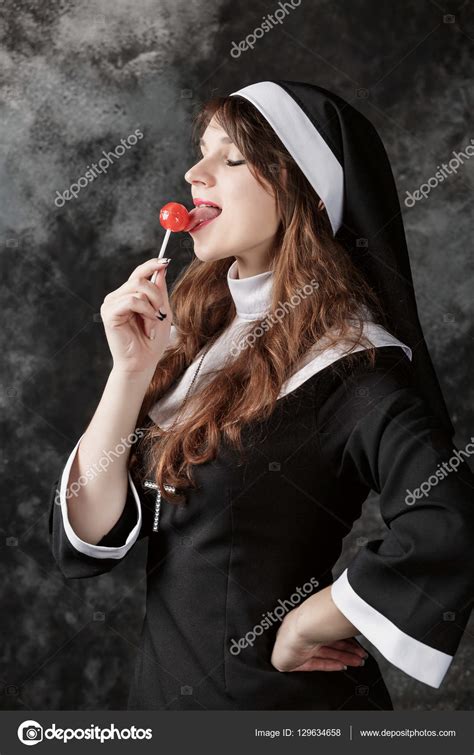 Young Sexy Nun In Stockings Licking A Red Candy On A Dark Background