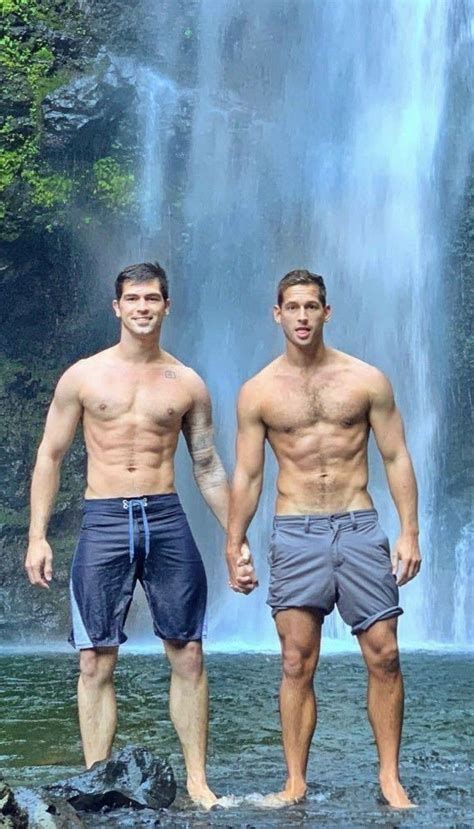 two men standing in front of a waterfall with no shirts on and one man without his shirt