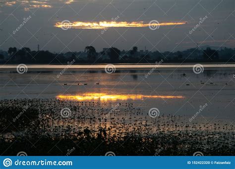 Golden Sunrise And Its Reflection In Water At The Lake Stock Photo