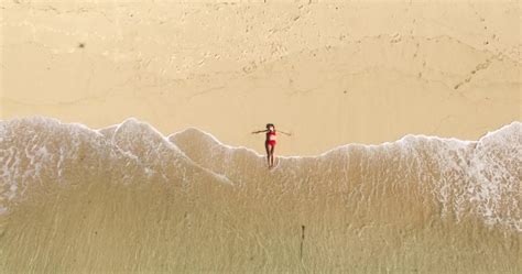 Aerial Top View Of Beautiful Girl In Red Bikini Lying On The Beach Sand With Calm Waves Stock
