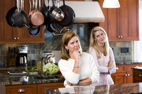 Madre Que Se Coloca En Cocina Con La Hija Adolescente Imagen De Archivo