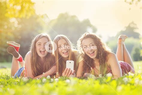 Three Beautiful Girls Laughing Together And Lying On Grass Outdoors In A Park Royalty Free