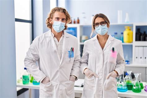 Man And Woman Wearing Scientist Uniform And Medical Mask At Laboratory