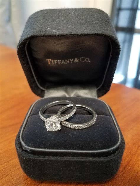 Whether you choose to go with an extravagant jewel or an understated band, this piece of jewelry is something that will indicate to the world and to yourselves. Tiffany and Co. Cushion Diamond Platinum Engagement Ring and Wedding Band Set For Sale at 1stdibs