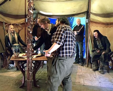 A Group Of Men Standing Around A Wooden Table In A Tent With People