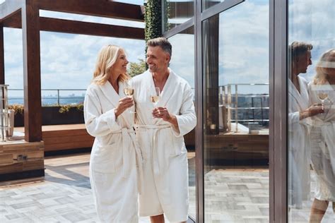 Premium Photo Beautiful Mature Couple In Bathrobes Enjoying Champagne While Relaxing In Luxury