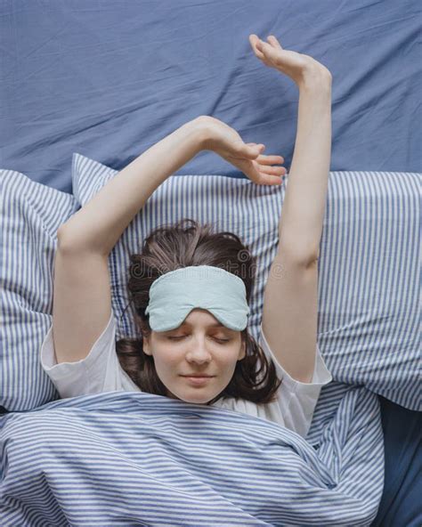 Top View Of A Woman In Bed Wearing A Sleep Mask A Happy European Woman Wakes Up And Stretches