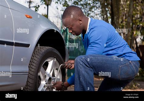 African Man Changing Tire On A Car Stock Photo Alamy