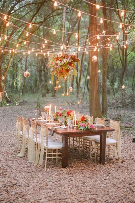 An Outdoor Dinner Table Set Up With Lights Strung From The Trees And