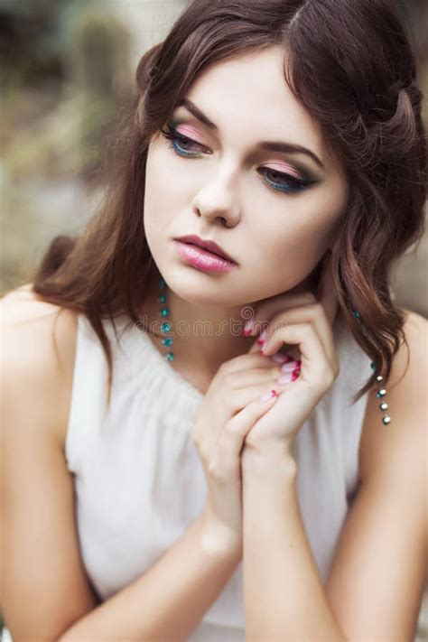 portrait of a beautiful brunette woman in pink dress and colorful make up outdoors in azalea