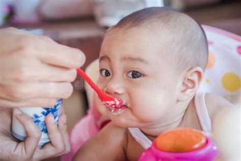 Cheerful Cute Baby Eating Baby Food On A Baby Chair Stock Image Image