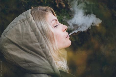 Ver Young Blonde Woman With A Hood On Blowing Smoke Out Her Mouth Del
