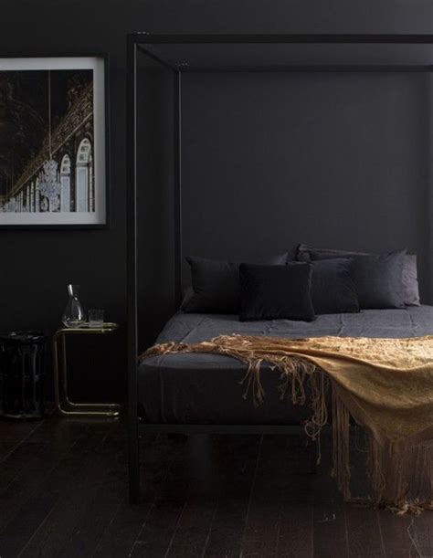 A Bed With Black Sheets And Pillows In A Dark Room Next To A Painting